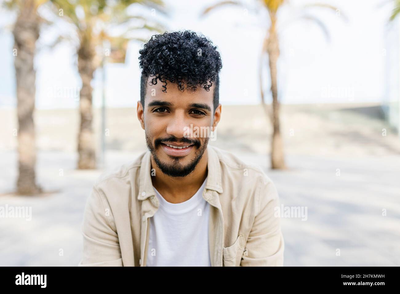 Smiling young bearded man with curly hair Stock Photo