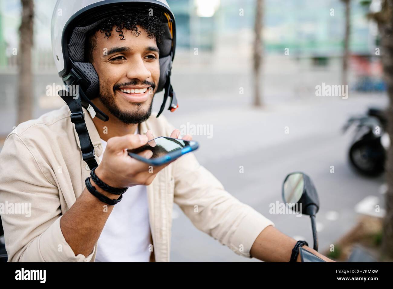 Man wearing crash helmet sending voicemail through smart phone Stock