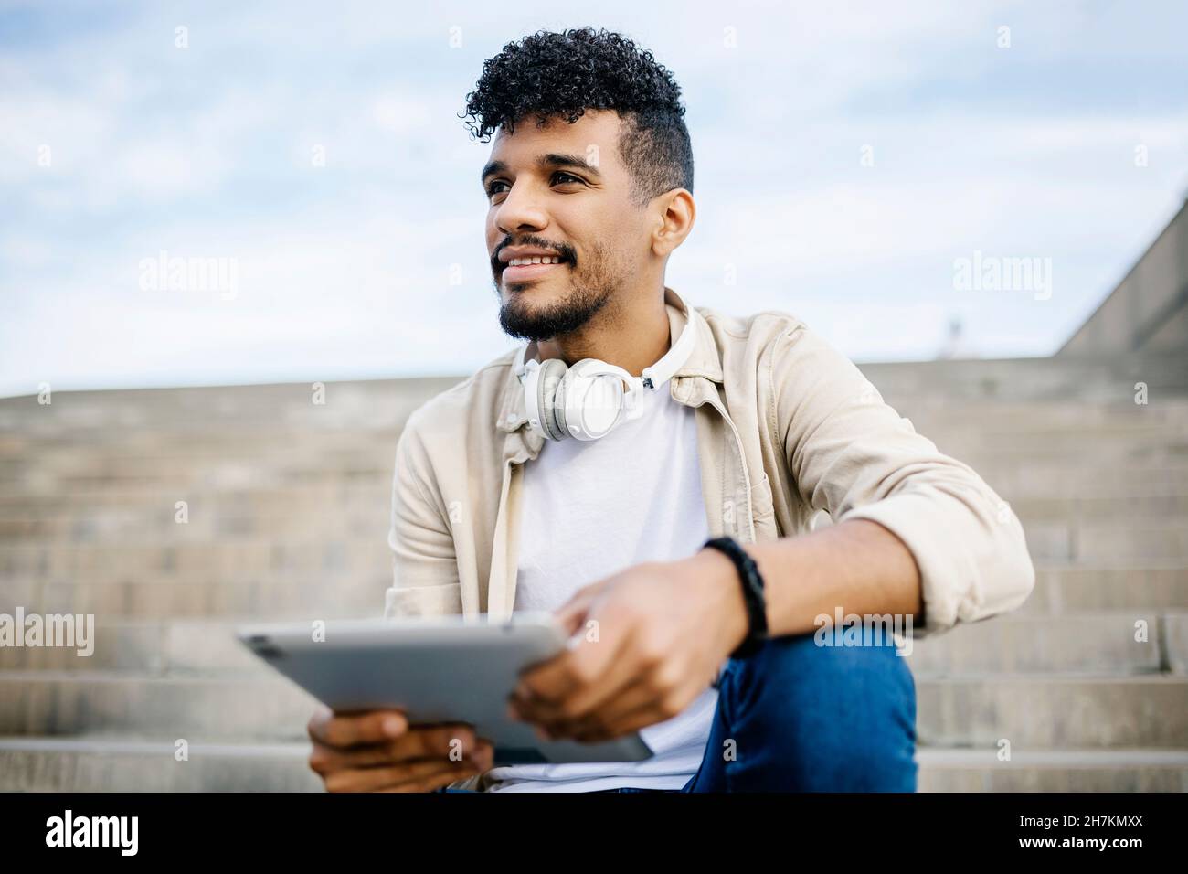 Bearded man holding digital tablet while sitting on steps Stock Photo