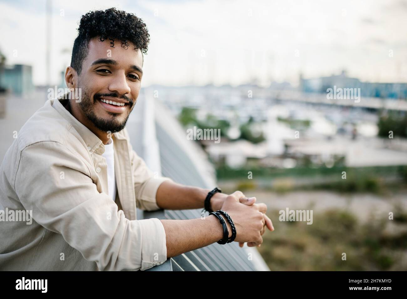Smiling young bearded man standing at building terrace Stock Photo
