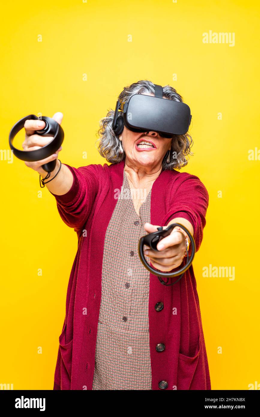 Senior woman pointing while wearing virtual reality headset against ...