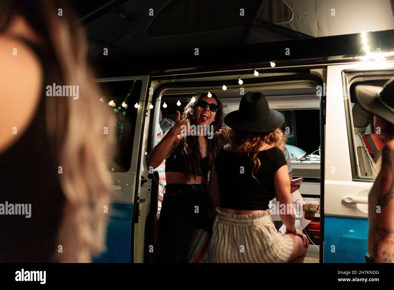 Woman showing shaka sign during party with female friends in camper van Stock Photo