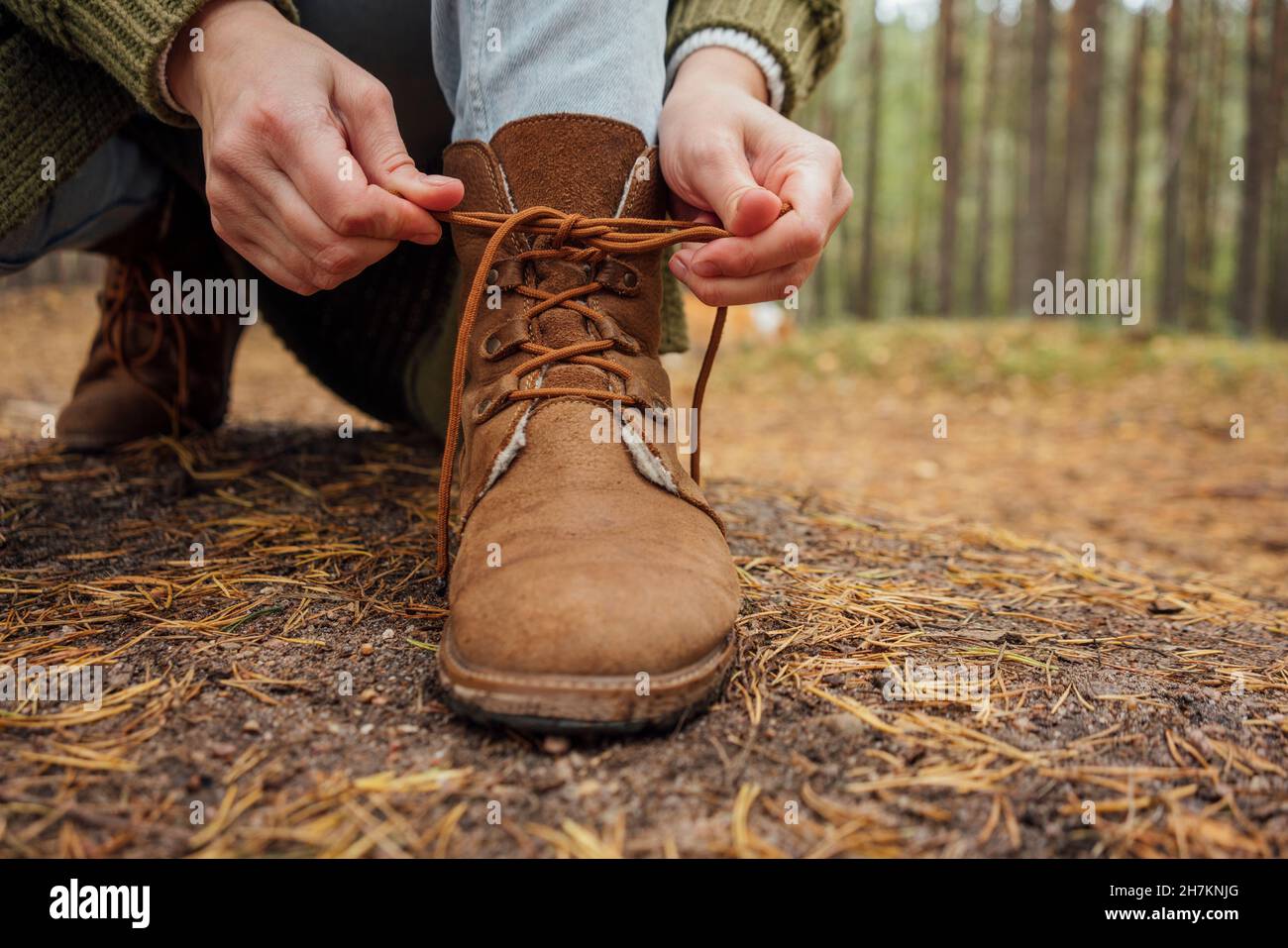 Woman tying shoelace of boot in forest Stock Photo