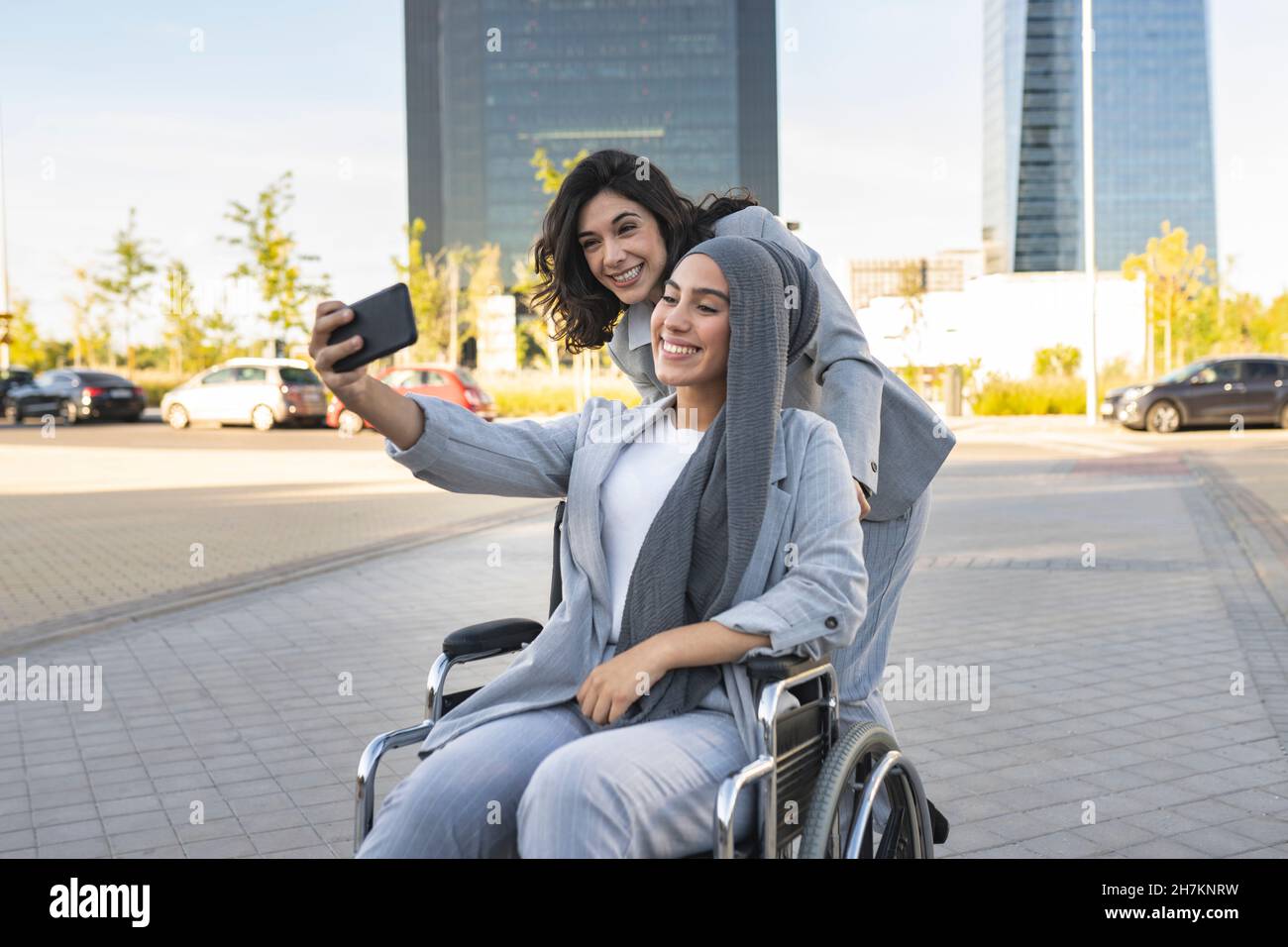 Cheerful female professionals gesturing while sitting on bench Stock Photo