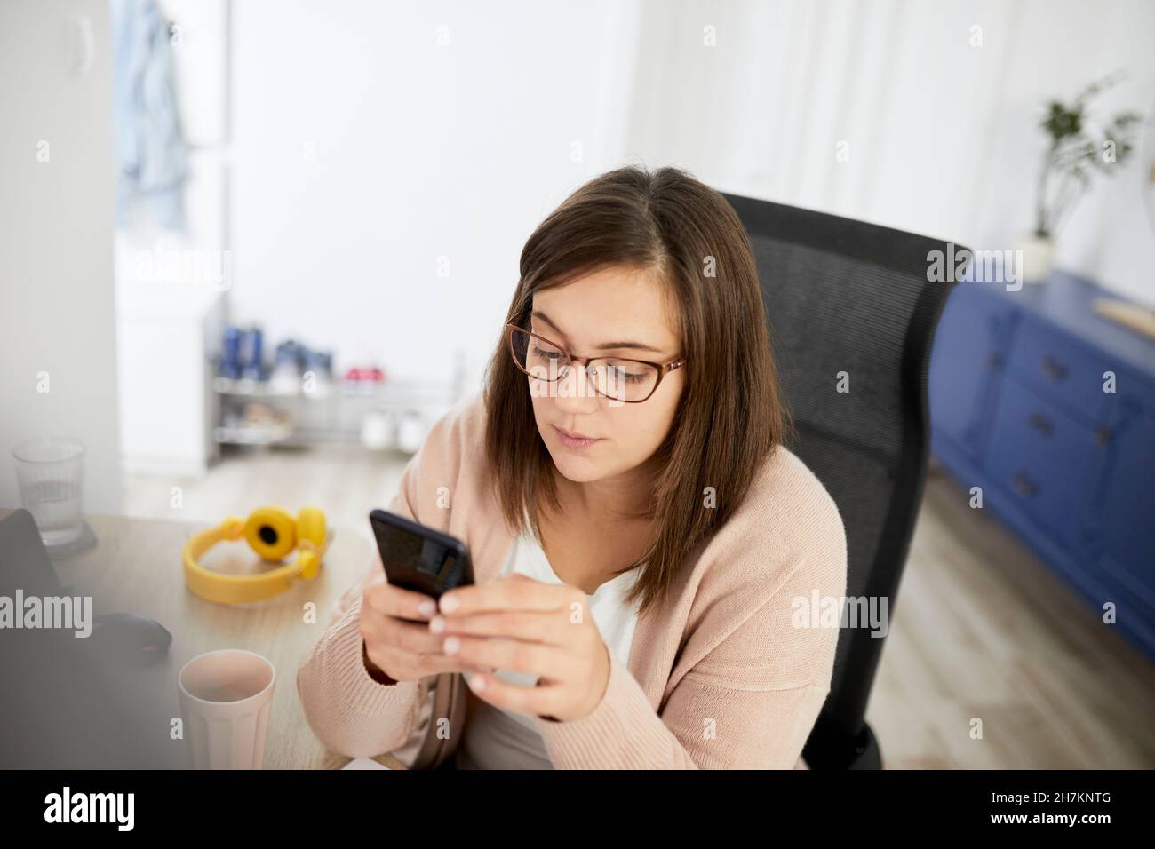 Female freelancer using smart phone while working at home Stock Photo
