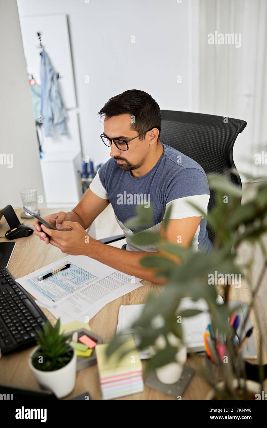 Businessman using smart phone while working at home office Stock Photo