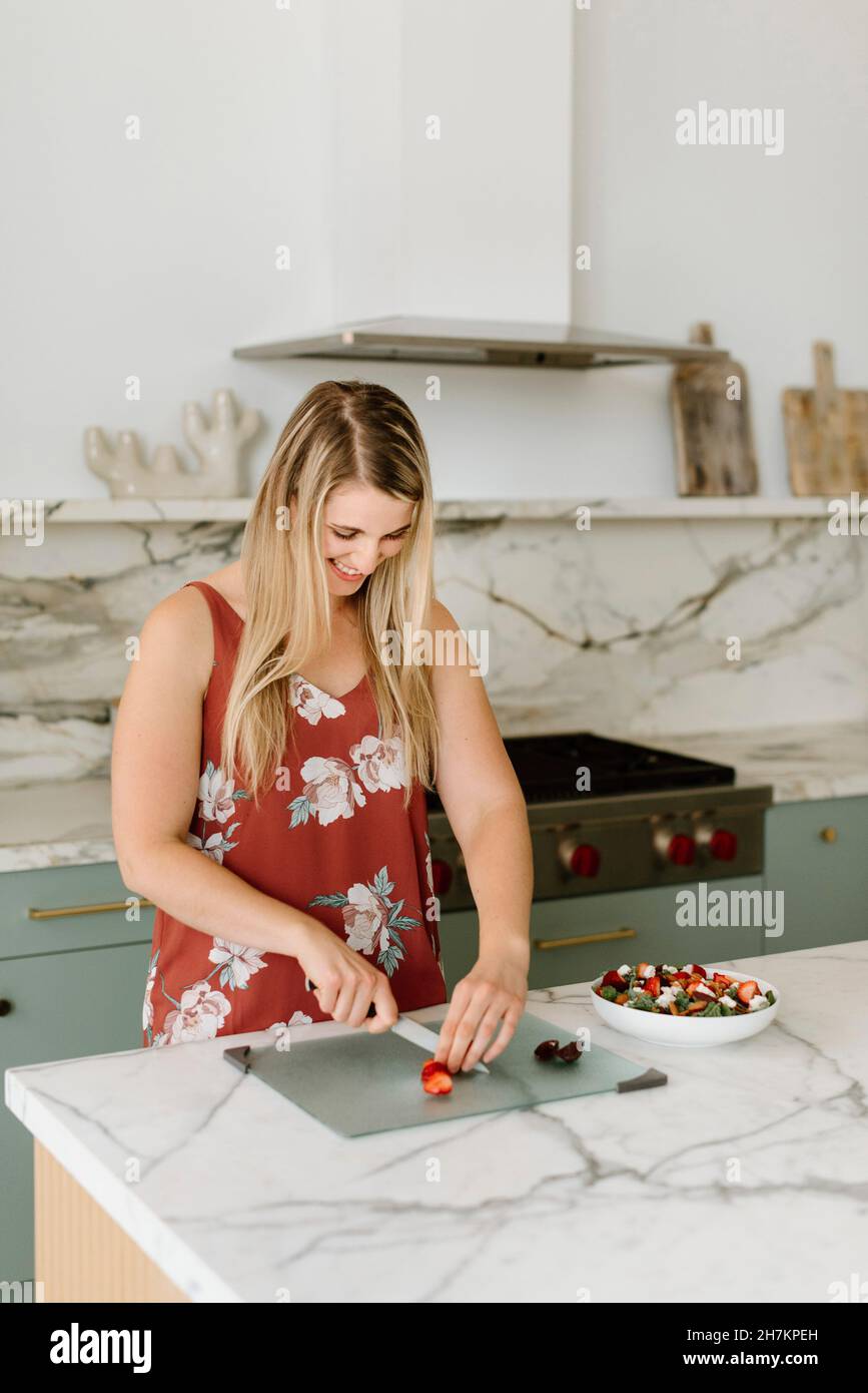 Female nutritionist cutting strawberry at kitchen counter Stock Photo