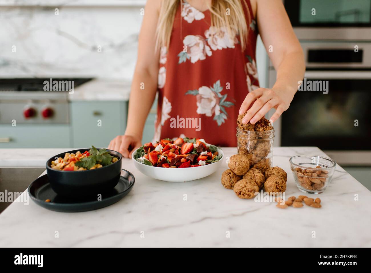 Female nutrient filling cookie in jar at kitchen counter Stock Photo