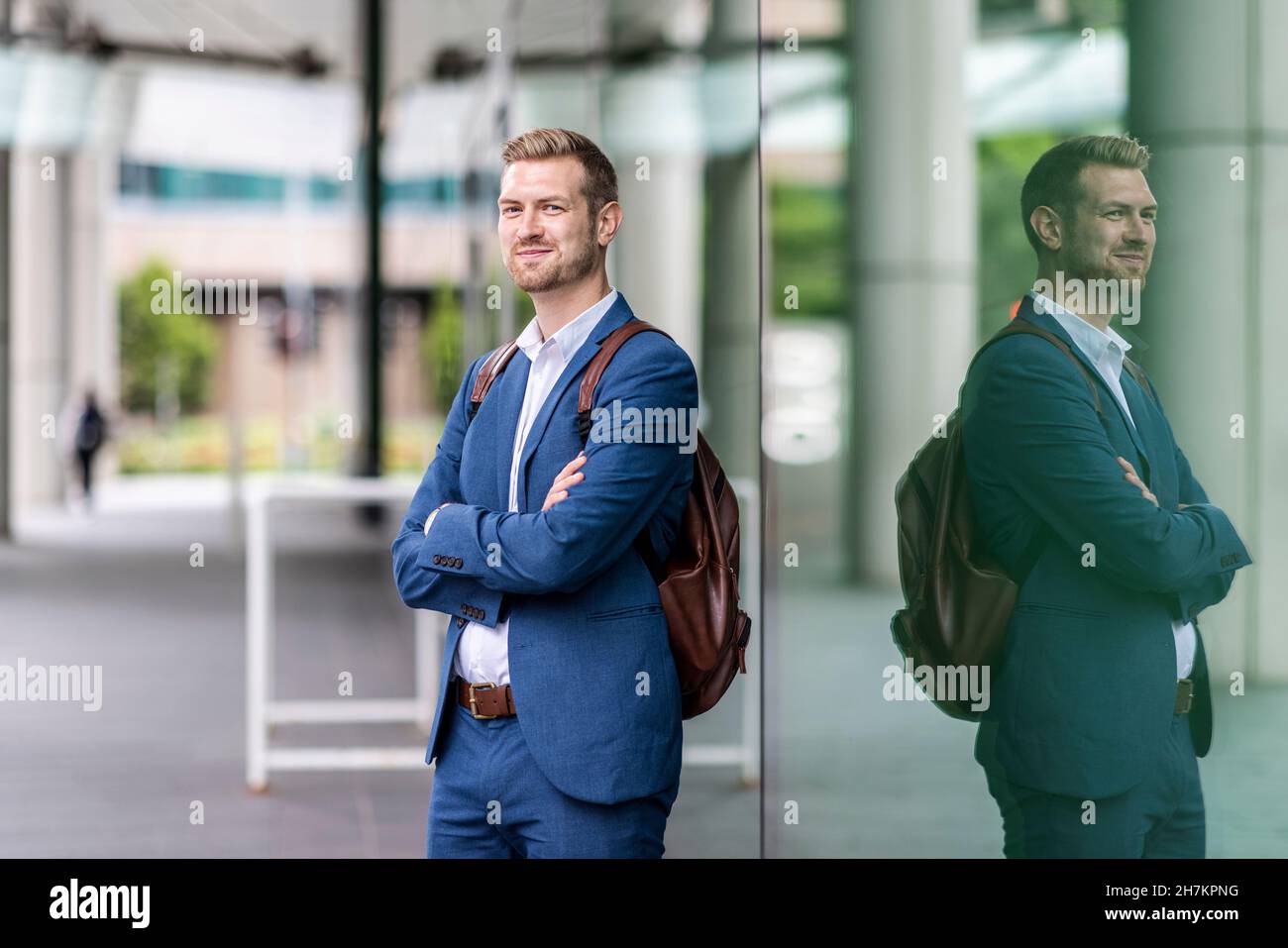 Smiling businessman standing with arms crossed by glass wall Stock ...