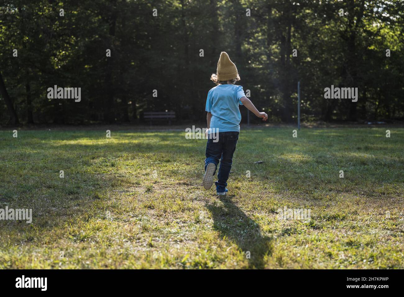 Boy wearing knit hat running on grass Stock Photo
