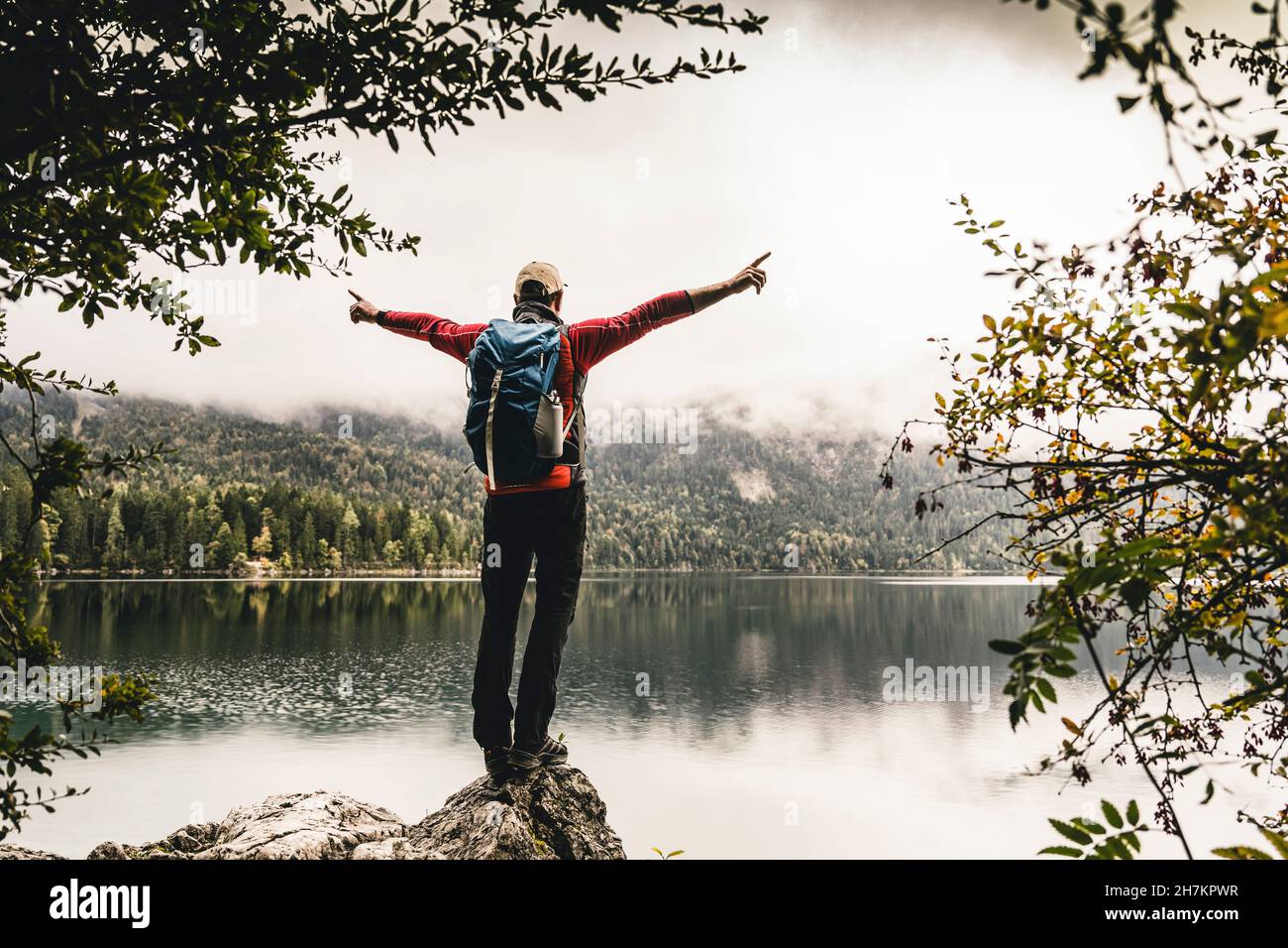 Male backpacker with arms outstretched standing on rock Stock Photo