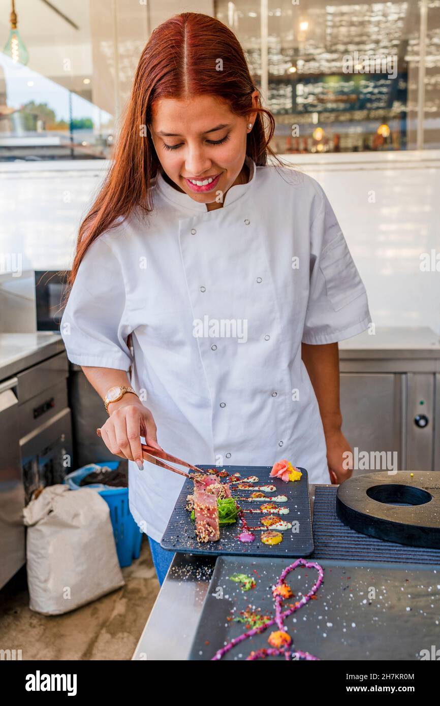 Smiling female chef decorating food in restaurant Stock Photo