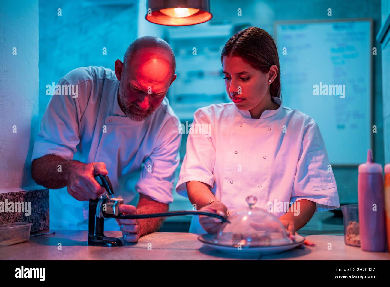 Male and female chefs using smoke infuser while cooking in kitchen
