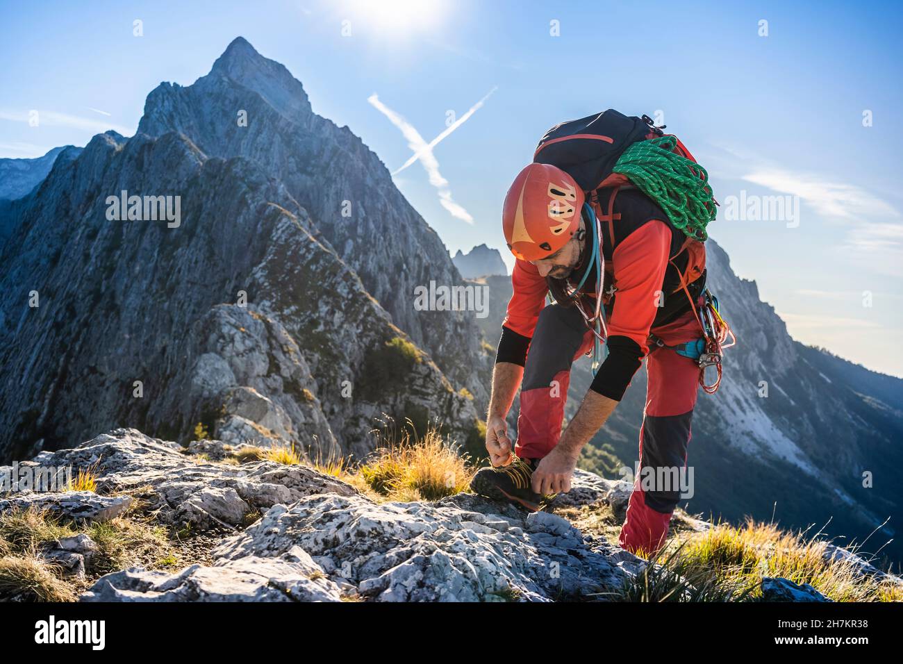 Mature male hiker tying shoelace on mountain Stock Photo