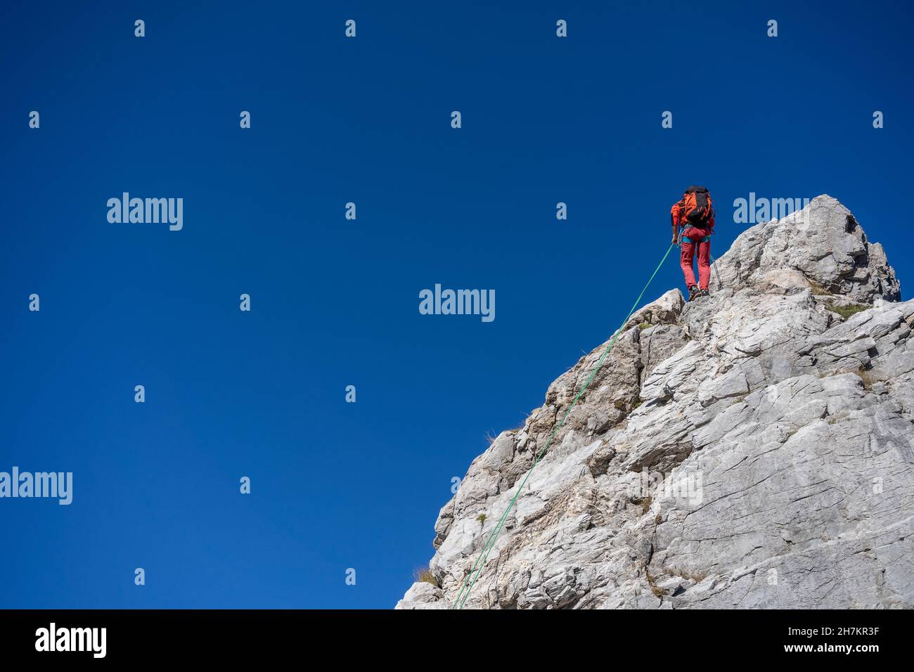 Male mountaineer climbing on Alpi Apuane hill with rope in front of clear sky Stock Photo