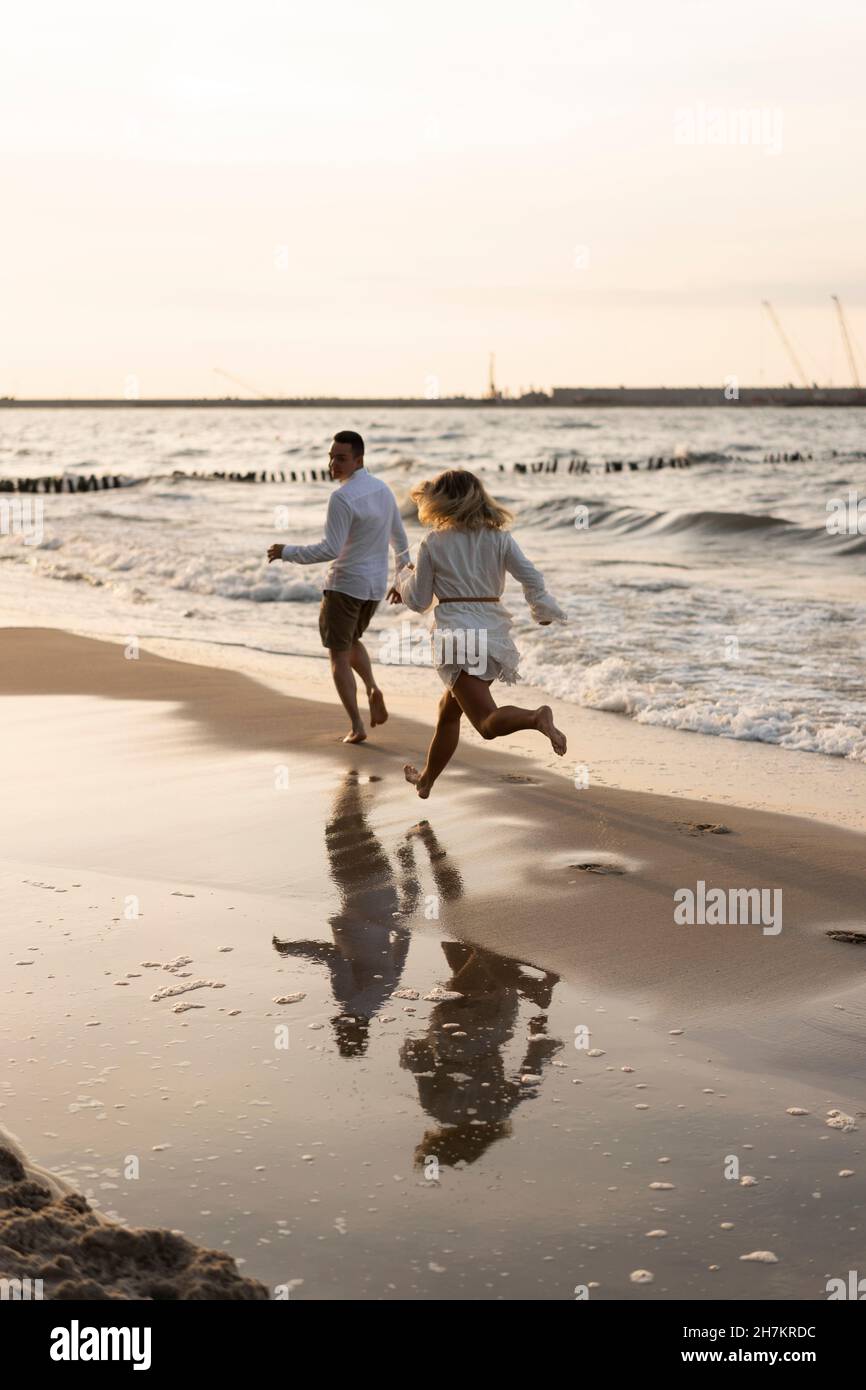 Young couple running at beach on sunset Stock Photo