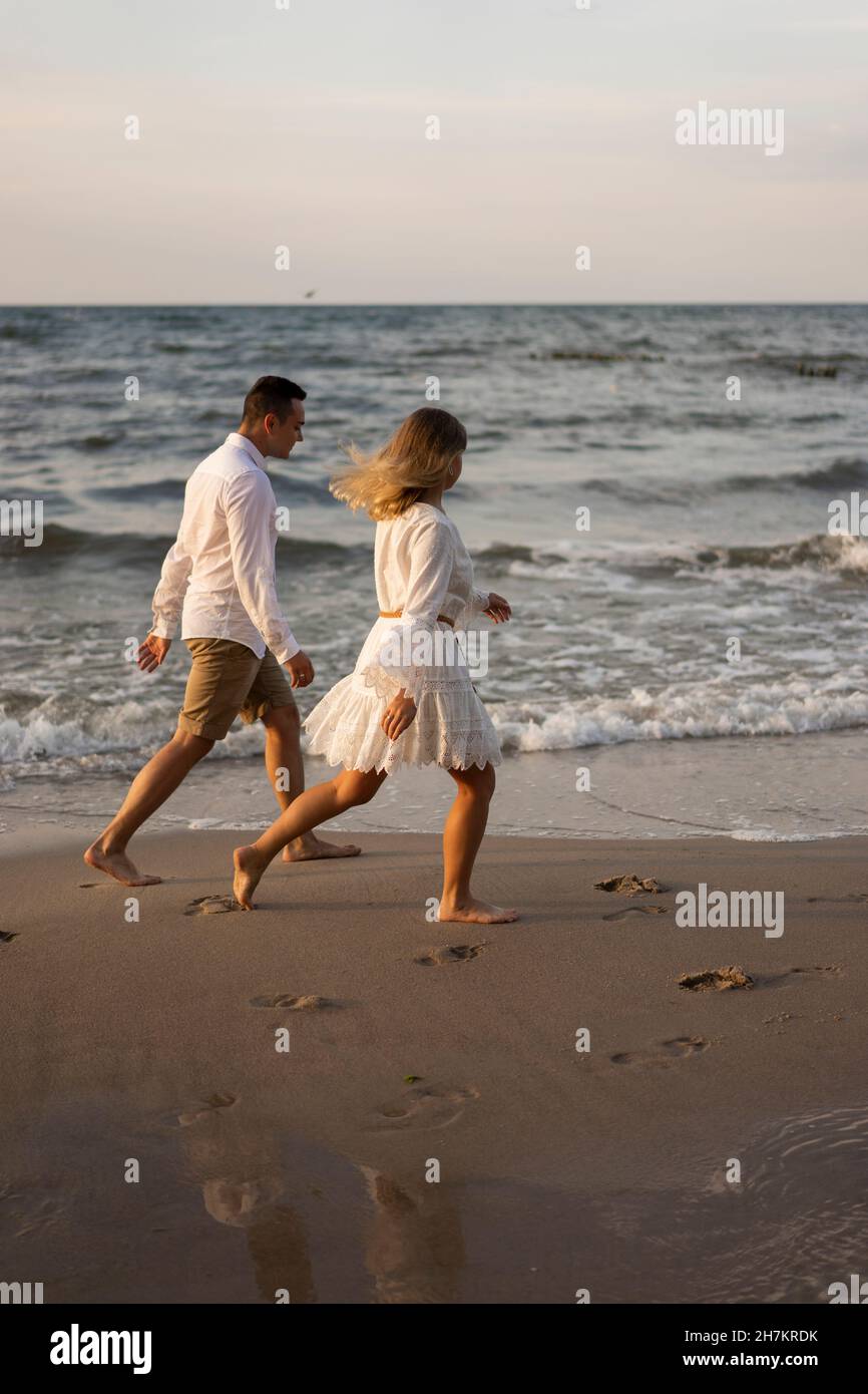 Couple running by sea at beach on sunset Stock Photo