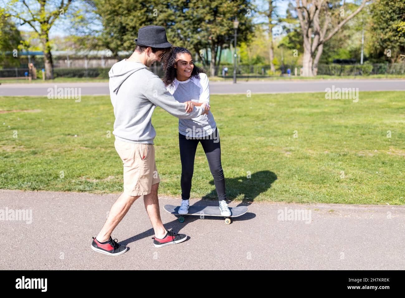 Man assisting friend while skateboarding in park Stock Photo