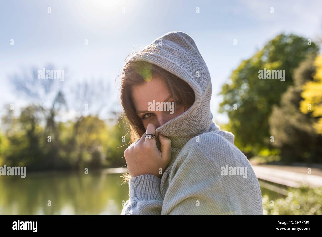 Young woman covering face with jacket in park Stock Photo - Alamy