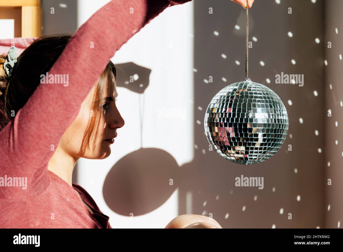 Young lonely woman holding shiny disco ball at home Stock Photo