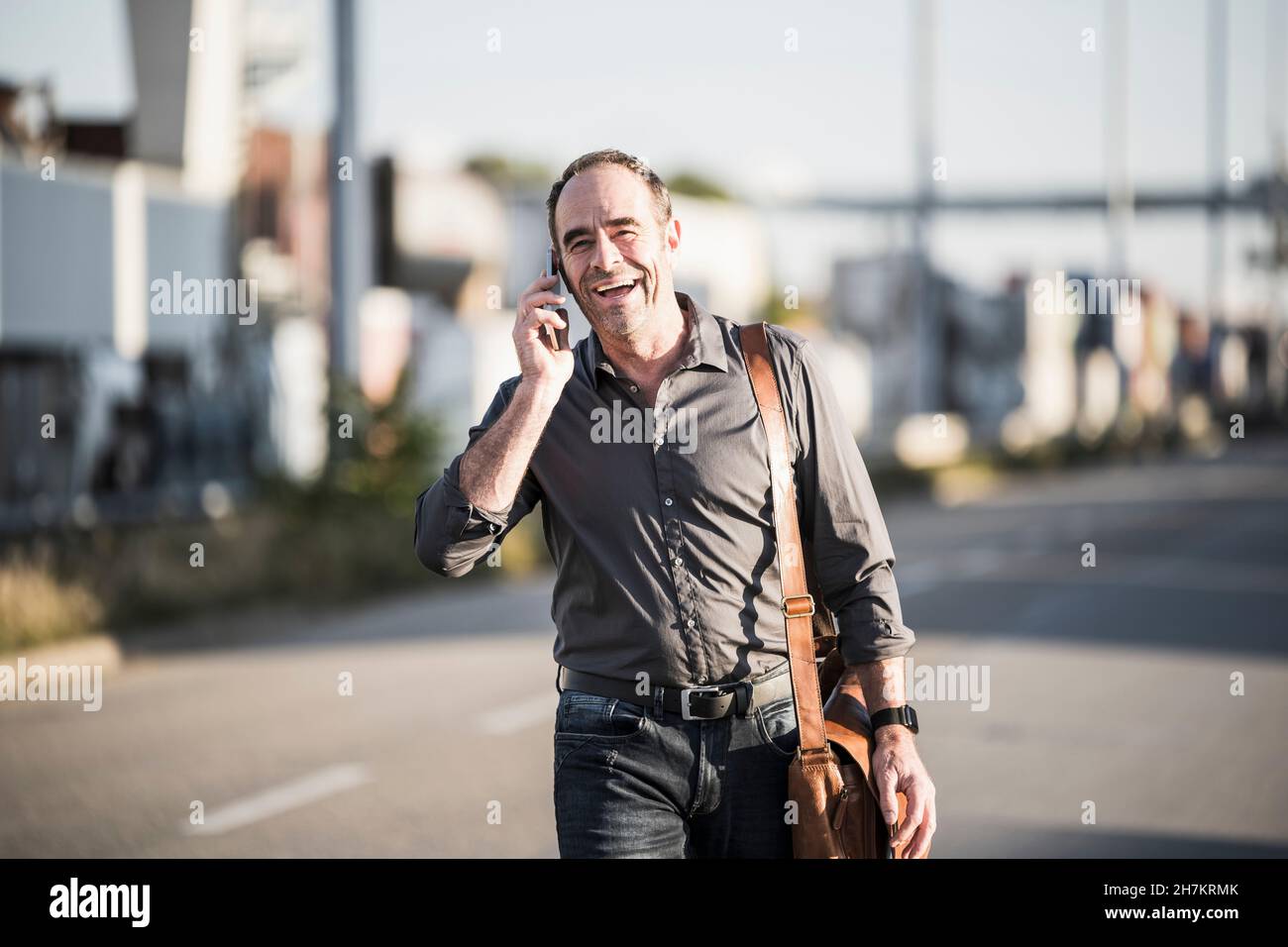 Cheerful businessman talking on smart phone while going for work Stock Photo