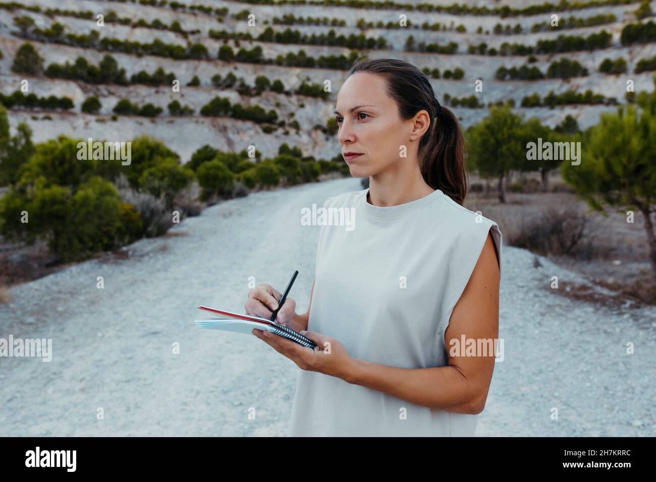 Female scientist collecting data in book while doing research in old mine Stock Photo