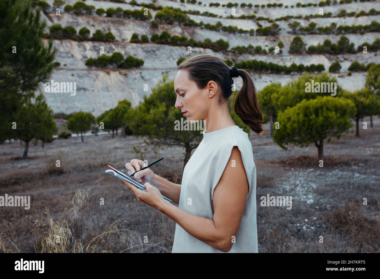 Female scientist writing data in book while doing research in field Stock Photo