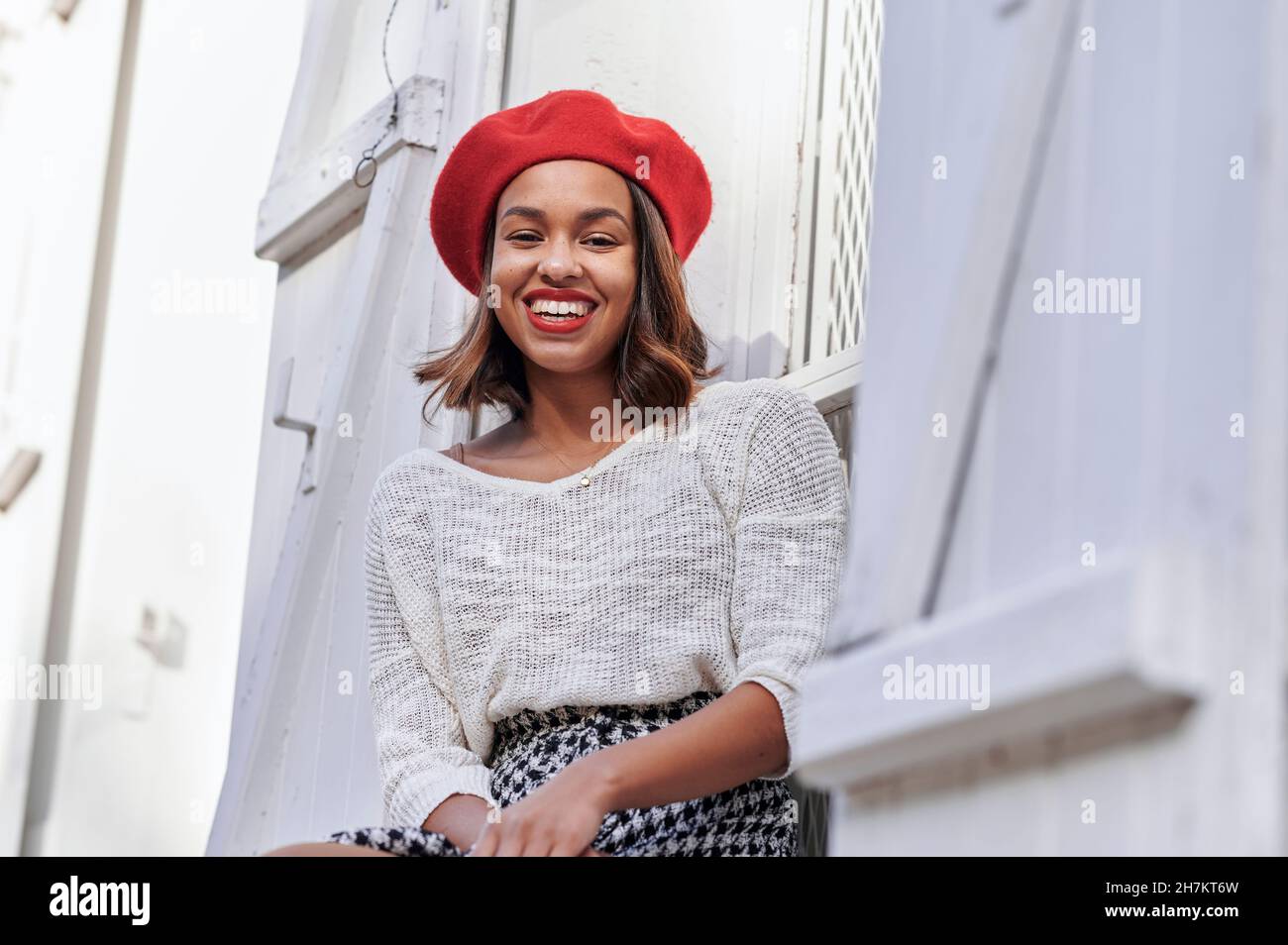 Smiling woman with beret sitting at window Stock Photo
