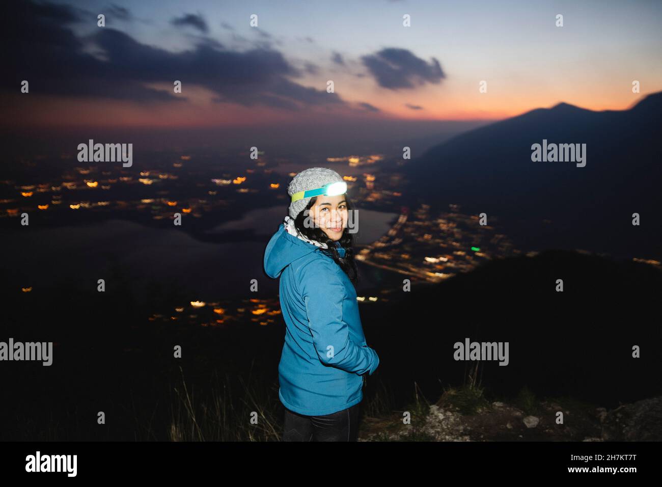 Hiker wearing head torch smiling on mountain Stock Photo