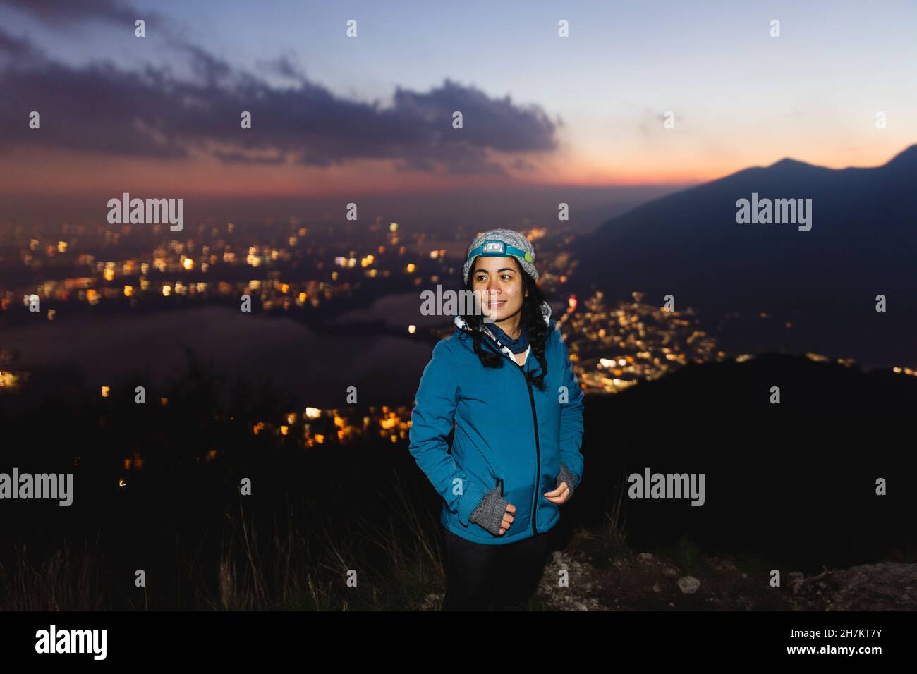 Young woman wearing head torch smiling on mountain Stock Photo