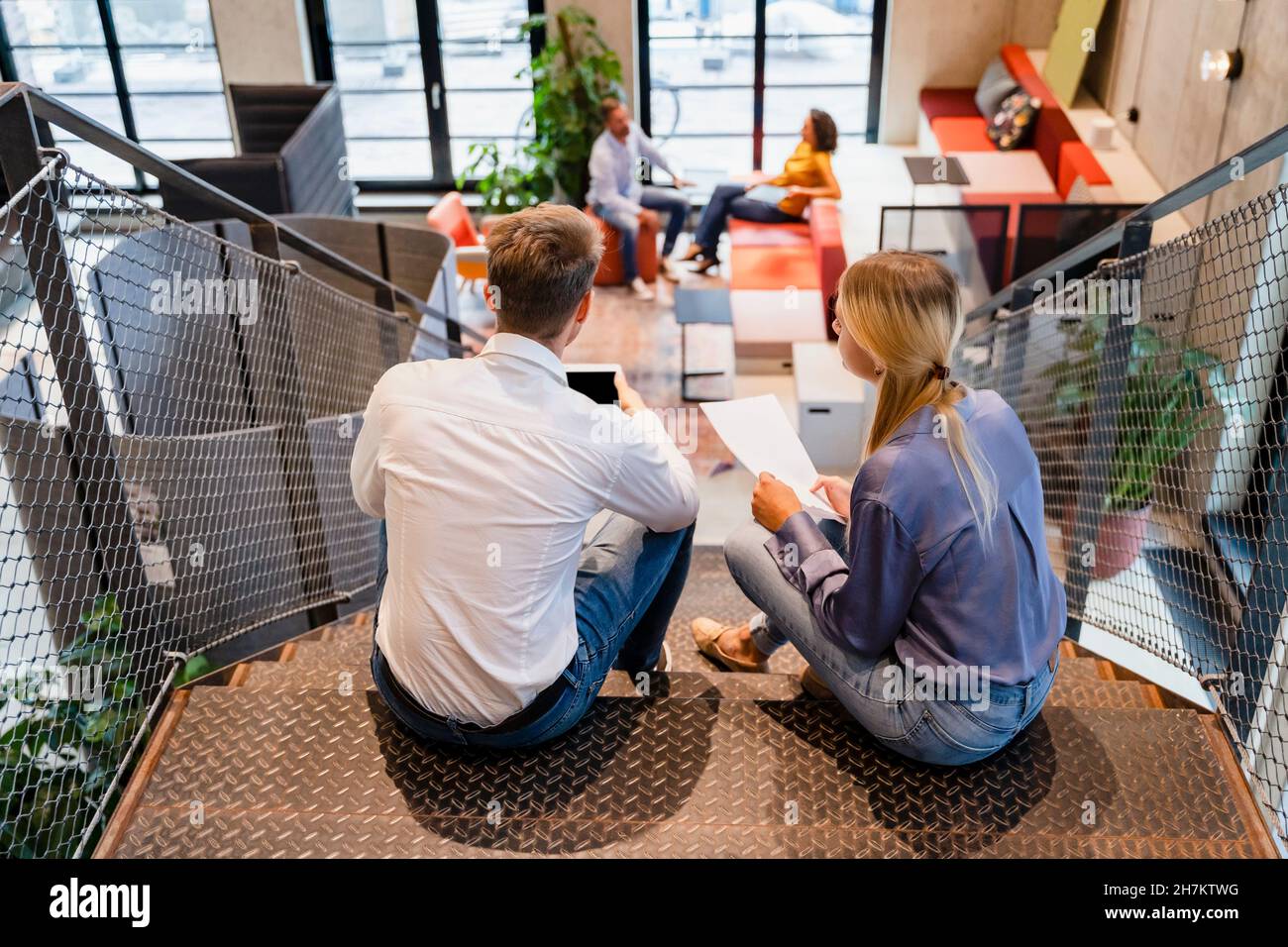 Young colleagues using tablet PC on office staircase Stock Photo