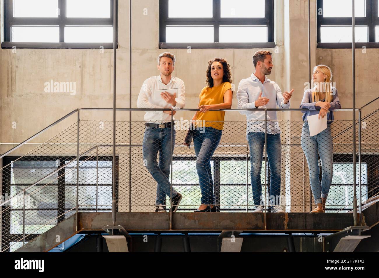 Coworkers having discussion at railing in office Stock Photo