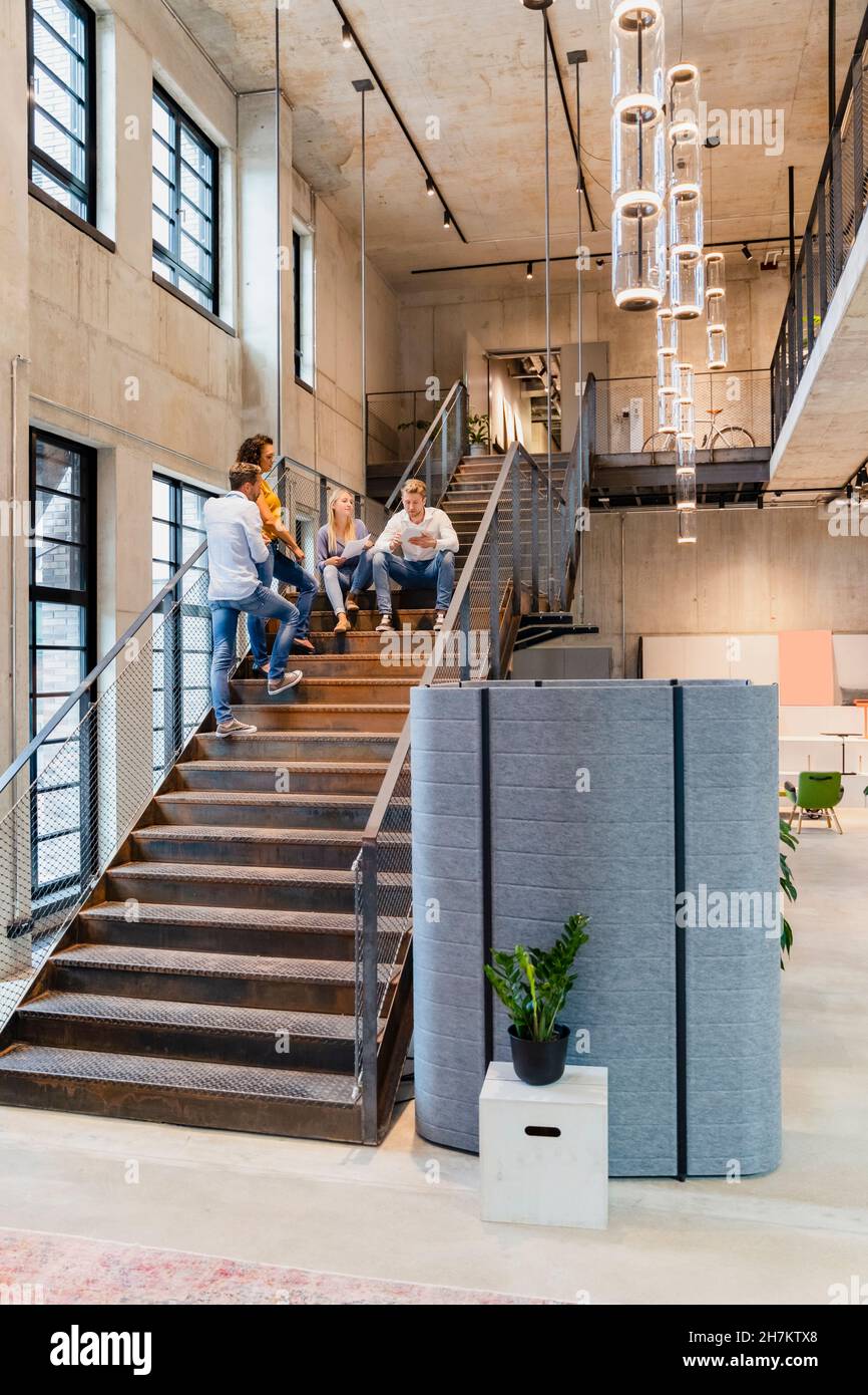 Coworkers having discussion on staircase in office Stock Photo