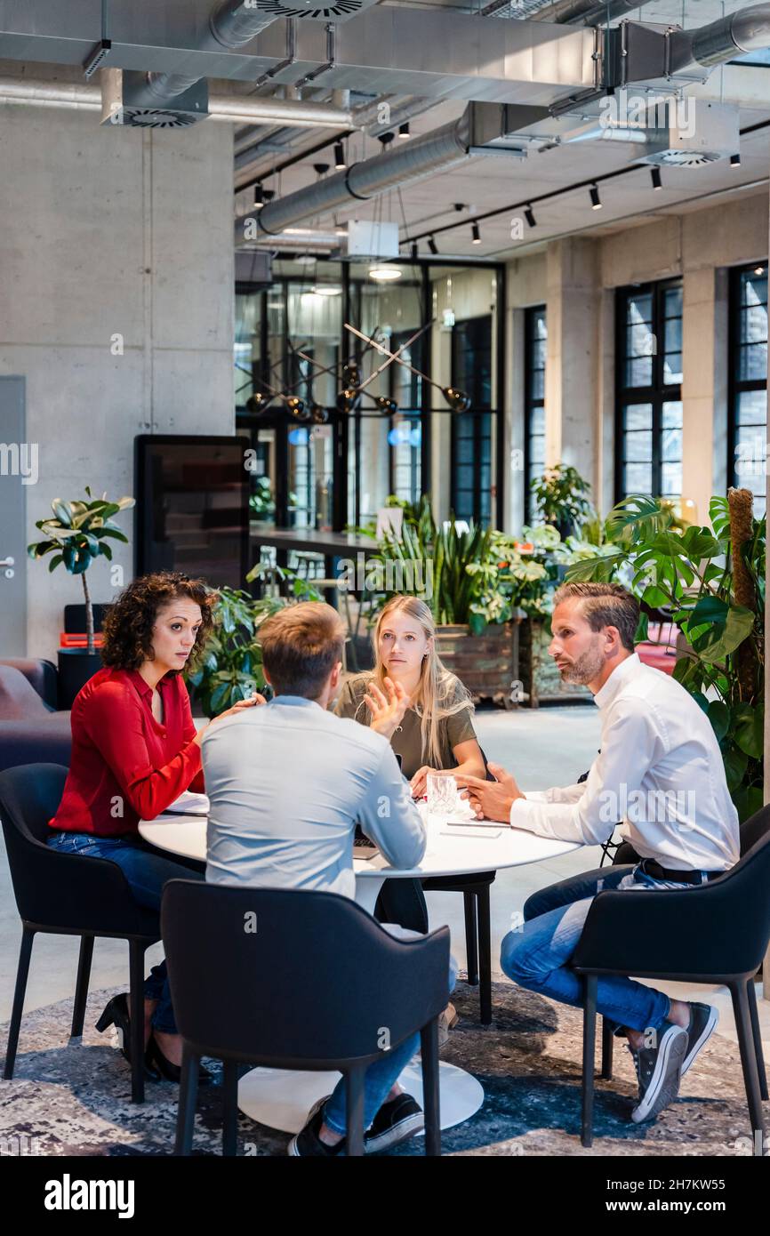 Colleagues having discussion while working at desk Stock Photo