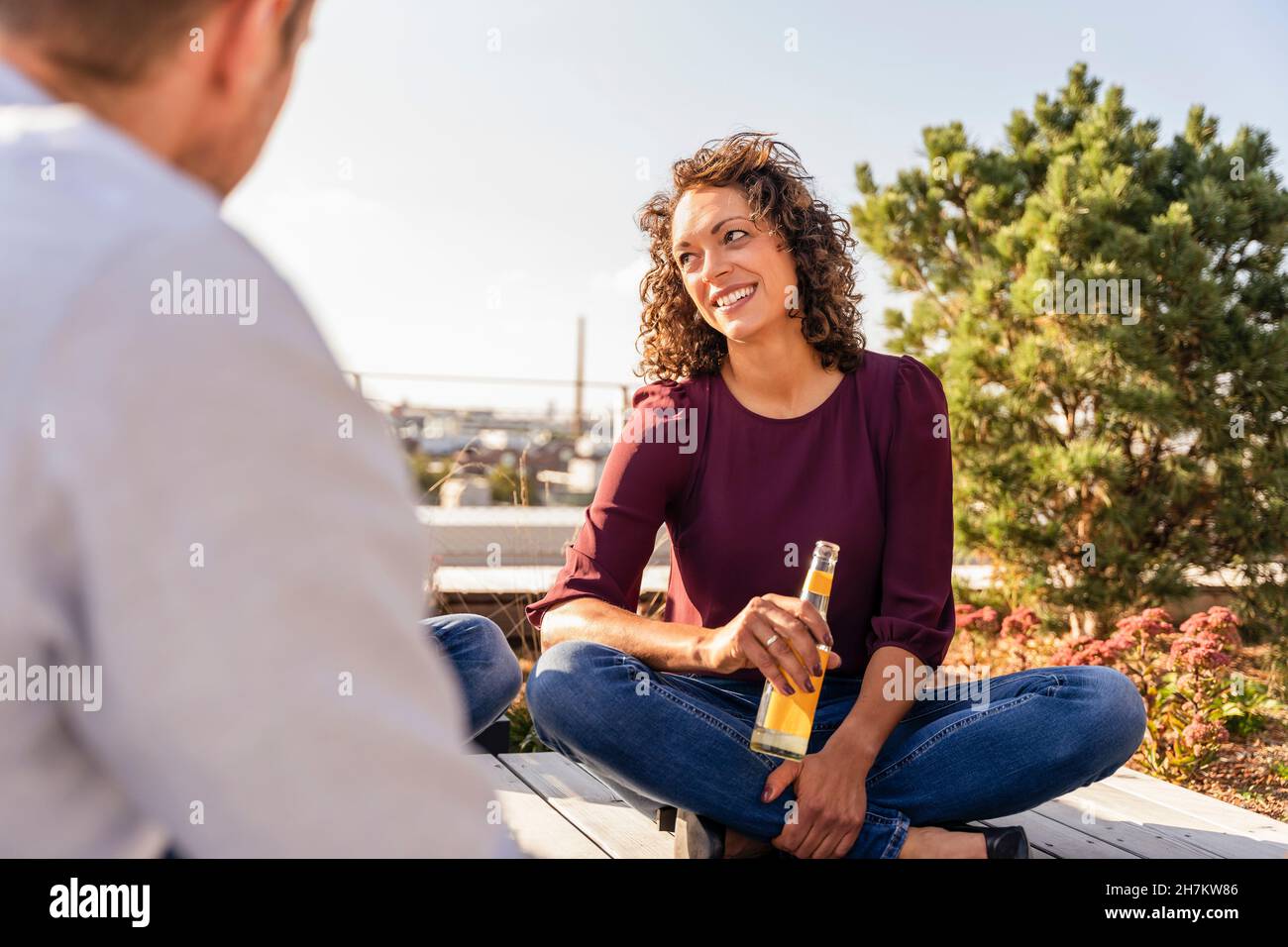 Smiling businesswoman having drink with colleagues on rooftop Stock Photo