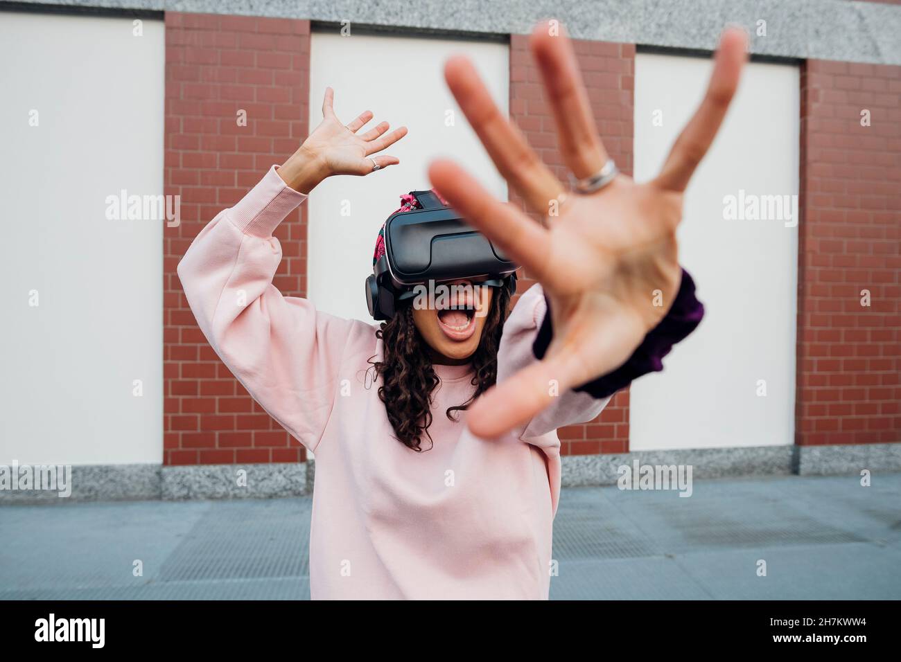 Woman screaming while using virtual reality headset on footpath Stock Photo