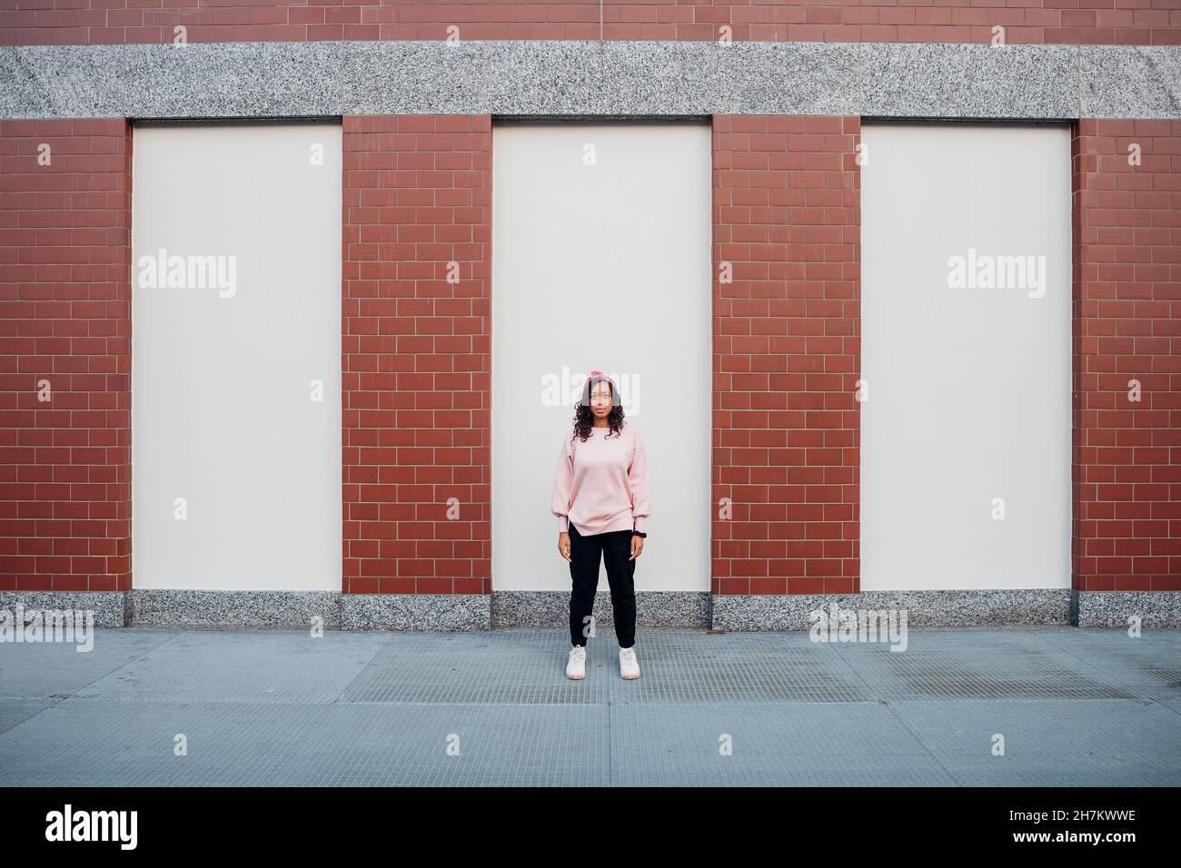 Woman standing in front of wall Stock Photo - Alamy