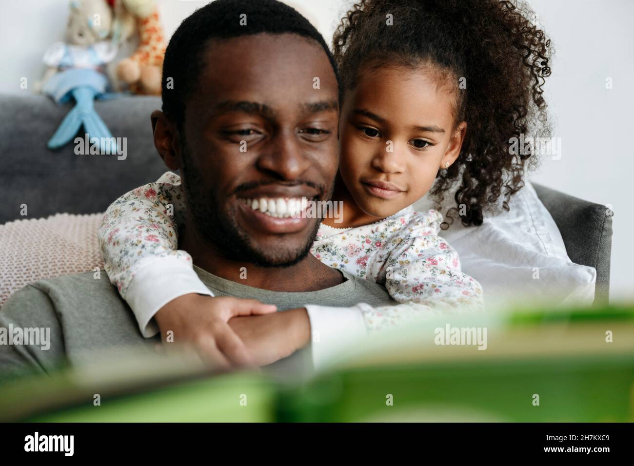 Smiling father telling story to daughter in living room Stock Photo
