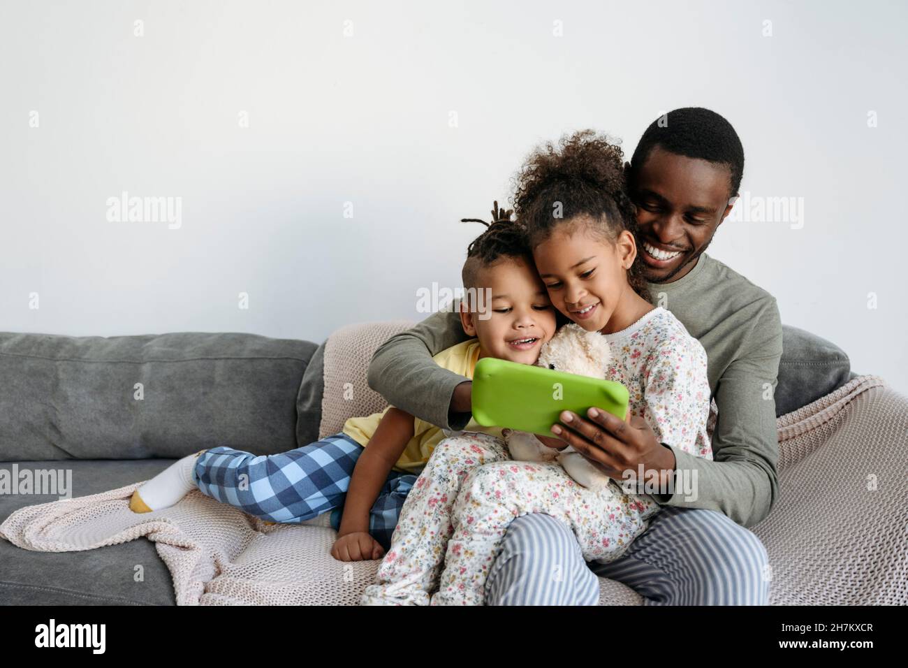 Smiling man with son and daughter using digital tablet on sofa Stock Photo