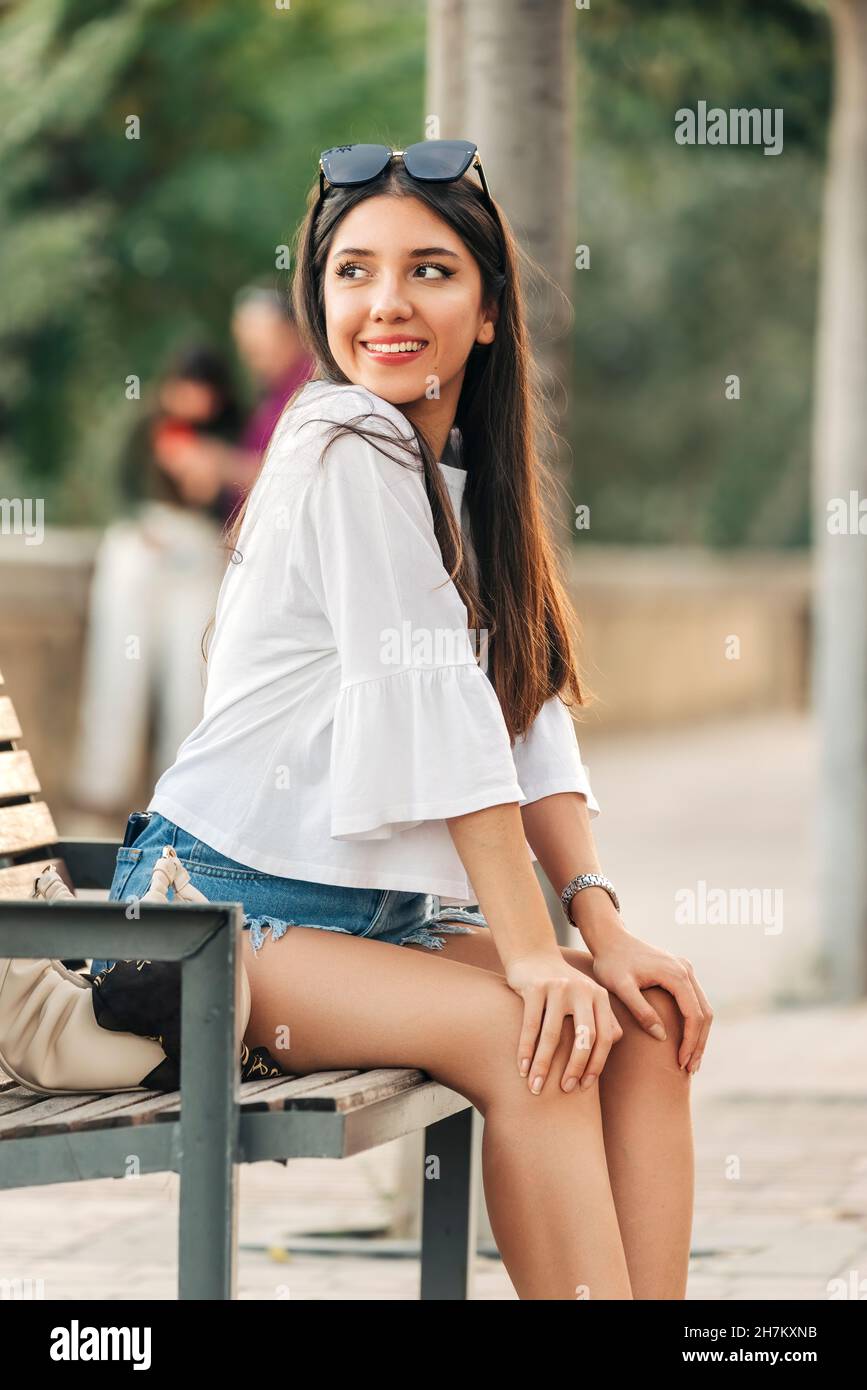 Young woman with hands on knee sitting on bench Stock Photo