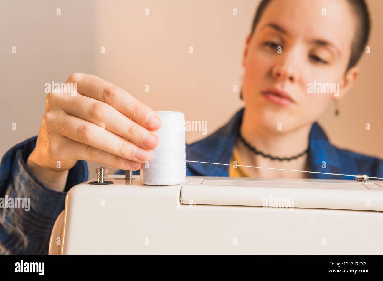 Female dressmaker placing spool of thread on sewing machine Stock Photo