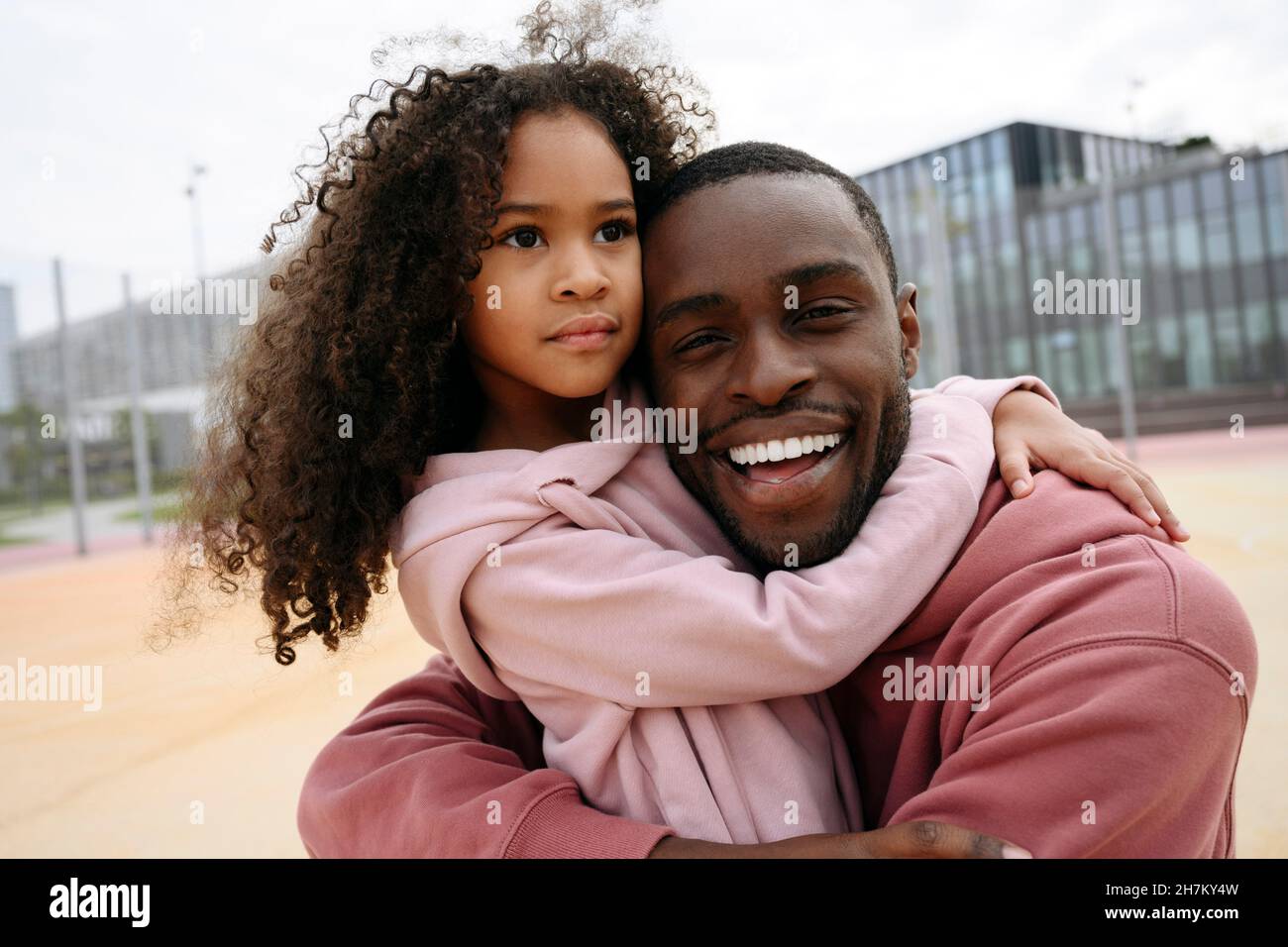 Happy man and girl hugging each other at sports field Stock Photo