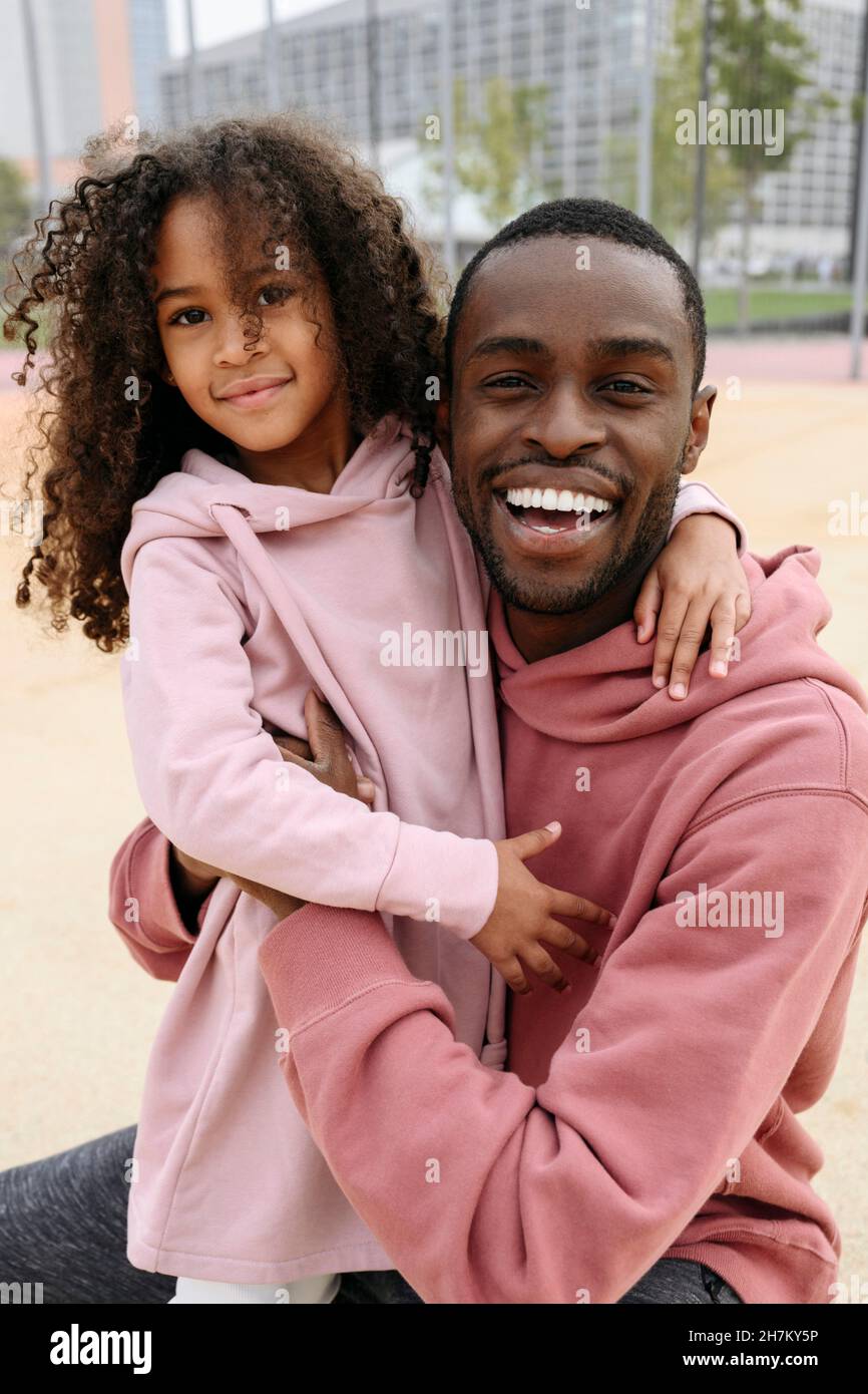 Smiling father hugging daughter at sports field Stock Photo