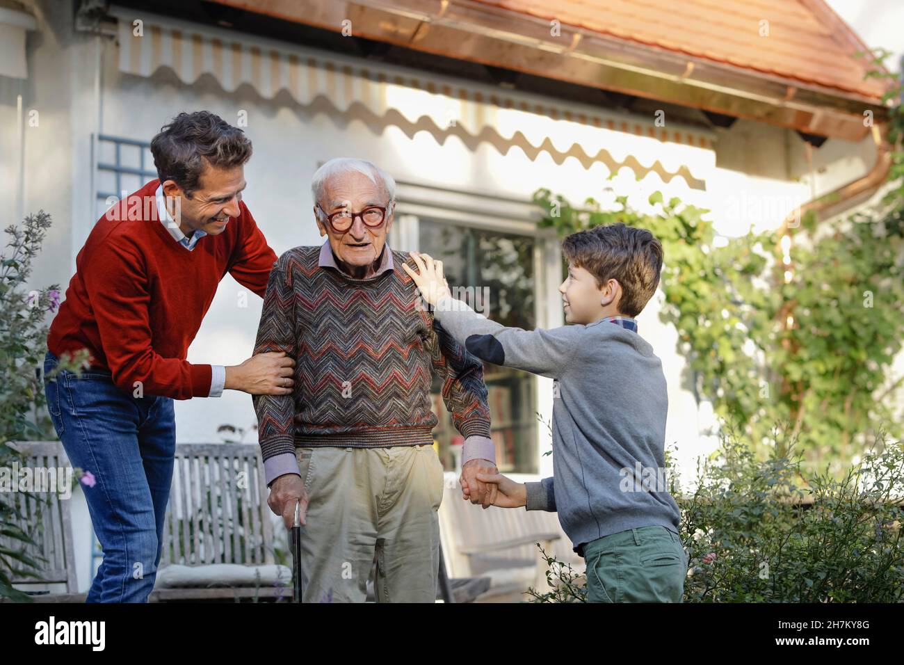 Smiling man with son consoling father in backyard Stock Photo