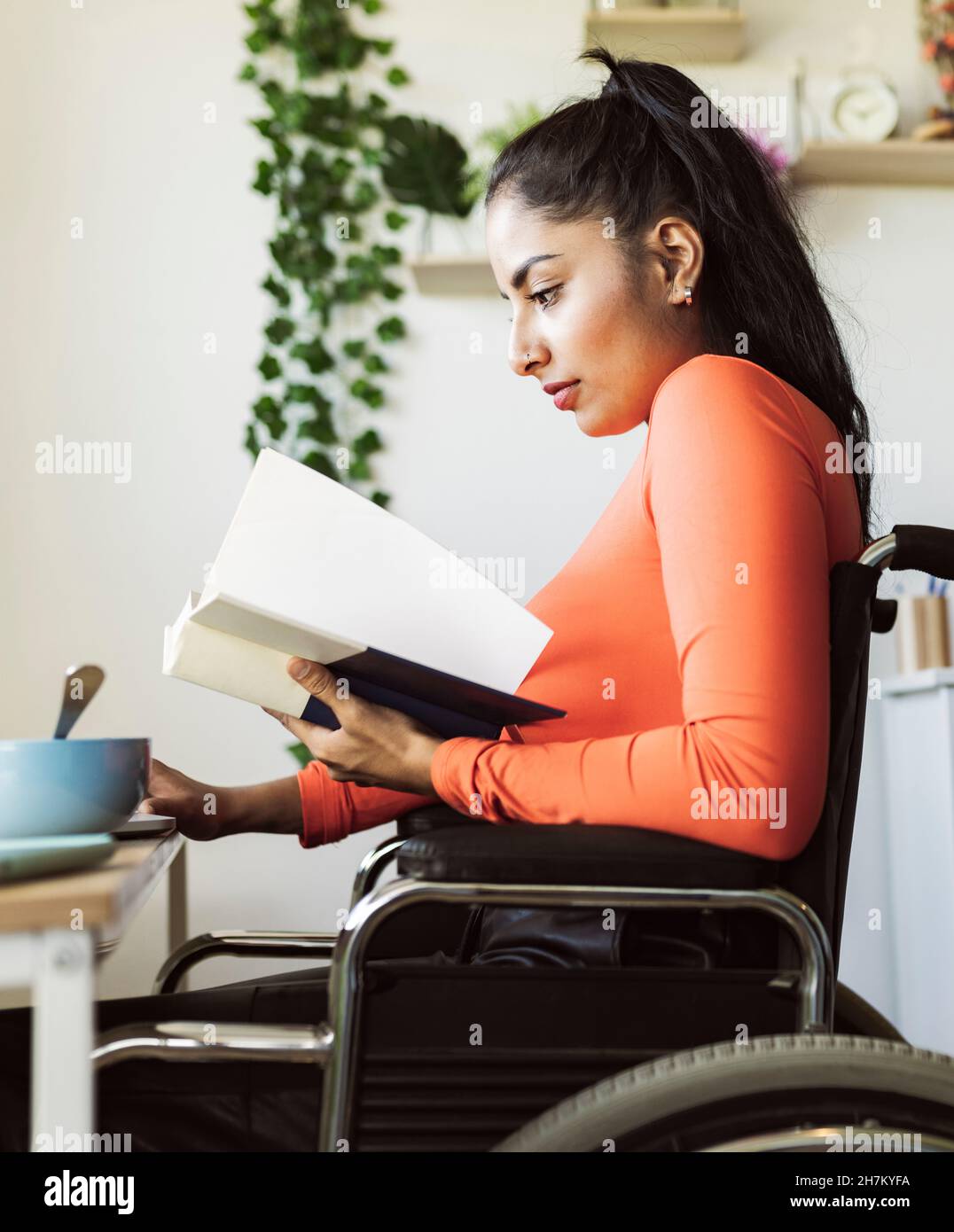 Smiling disable woman with food using laptop at home Stock Photo