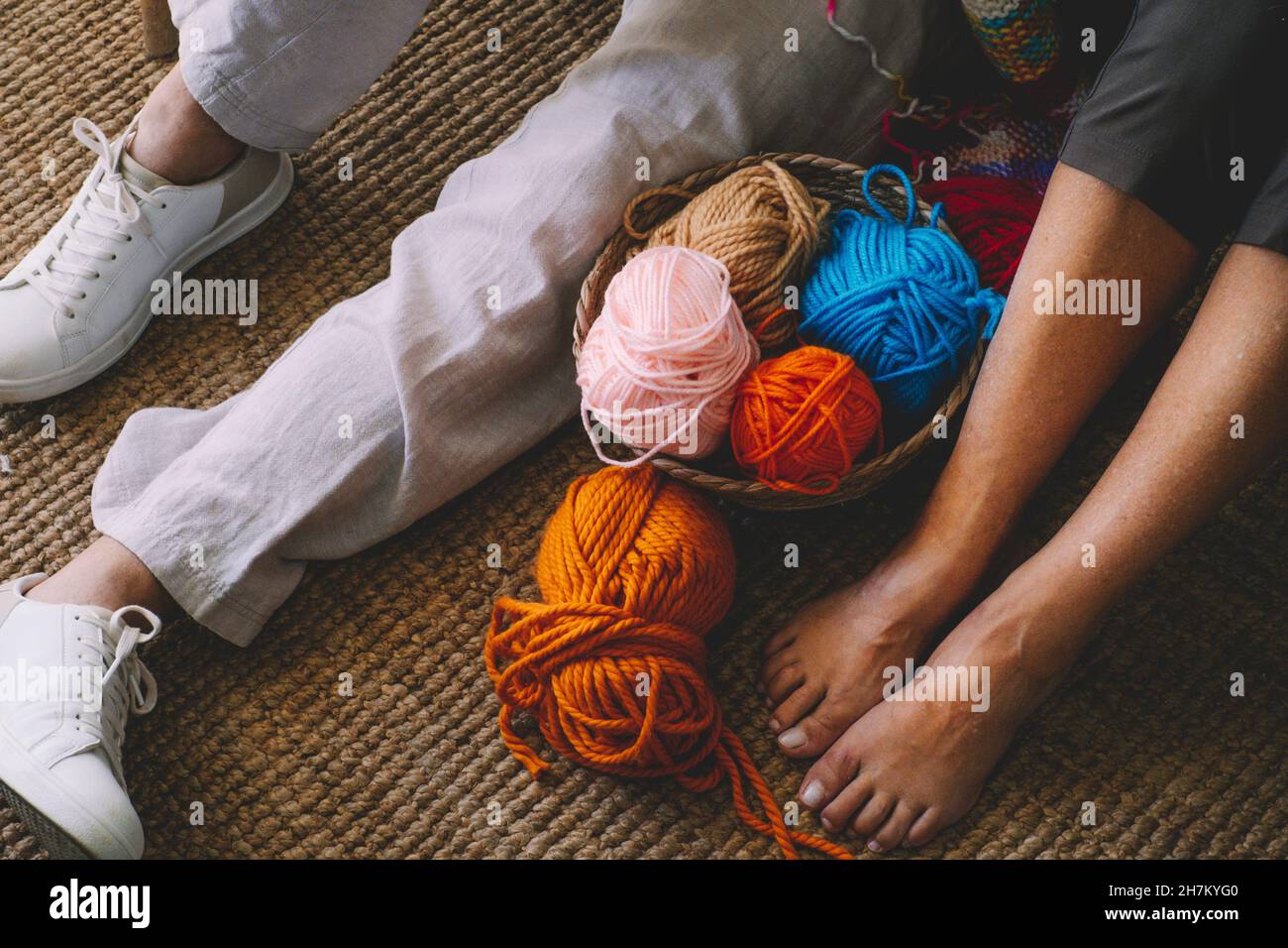 Couple sitting with balls of wool in basket at home Stock Photo