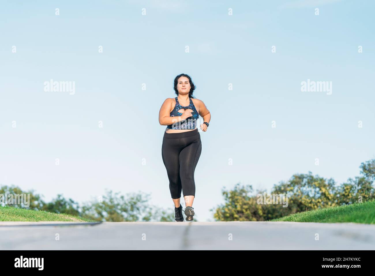 Plus size sportswoman running on road Stock Photo