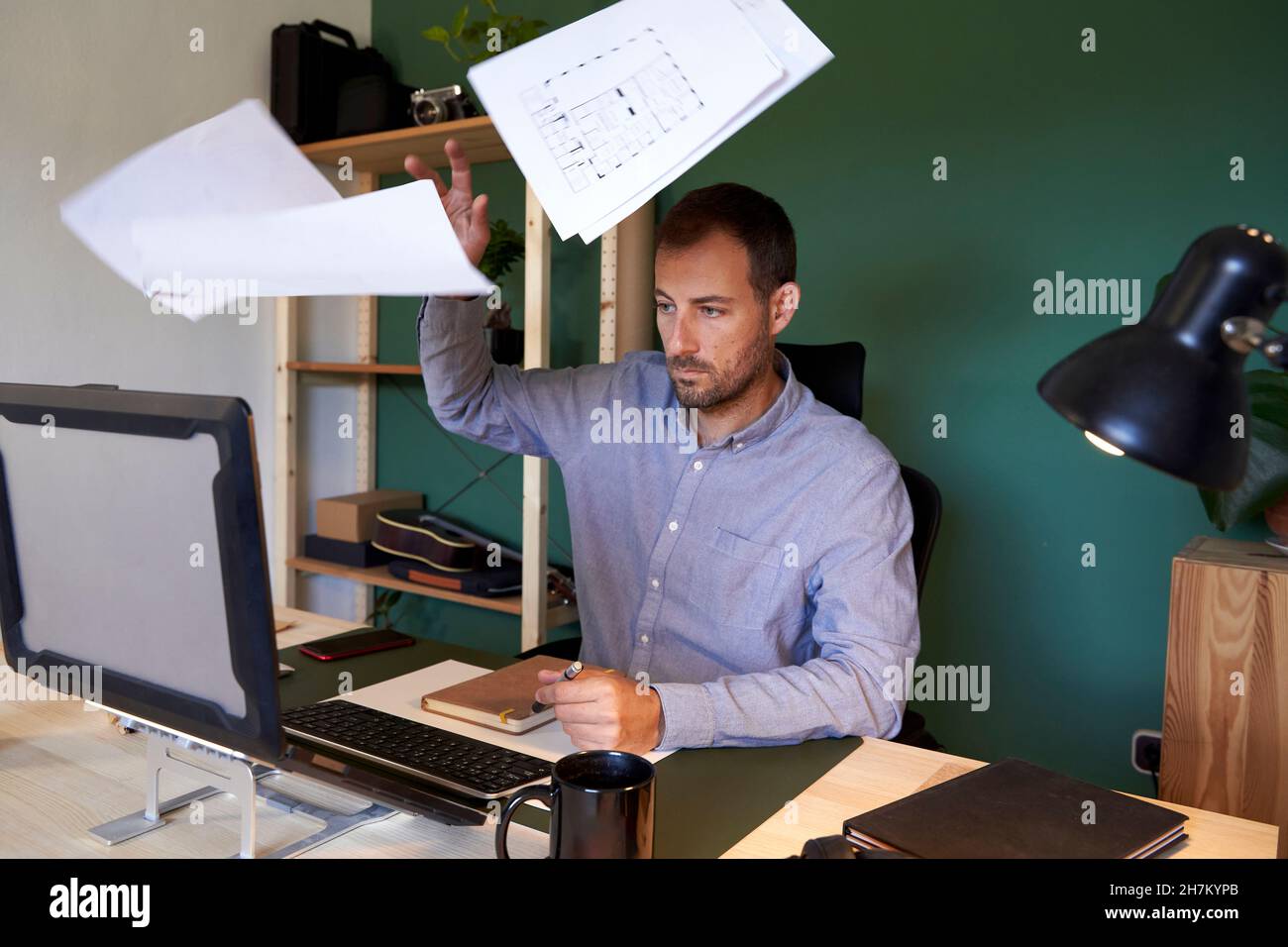 Overworked freelancer throwing documents at home office Stock Photo