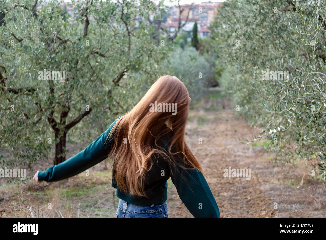 Redhead woman running amidst trees at farm Stock Photo Alamy