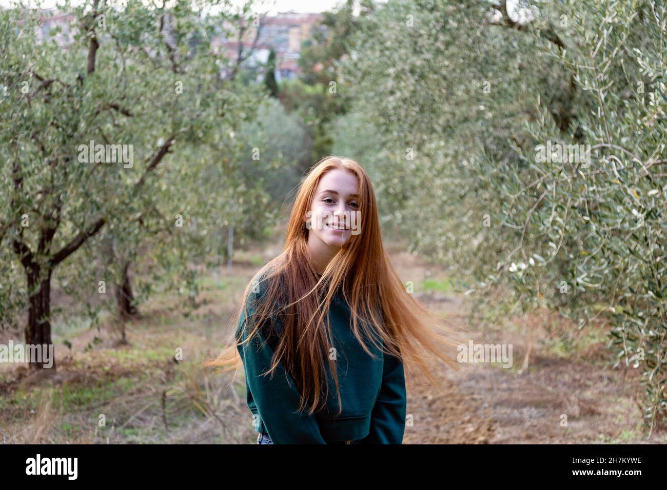 Smiling redhead woman at olive groove Stock Photo